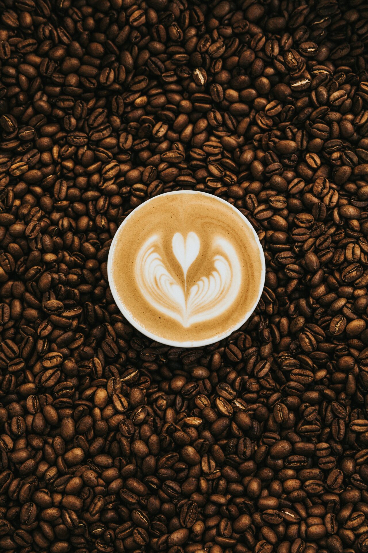 cup of coffee surrounded by coffee beans